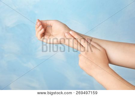 Woman Checking Pulse On Wrist Against Color Background, Closeup