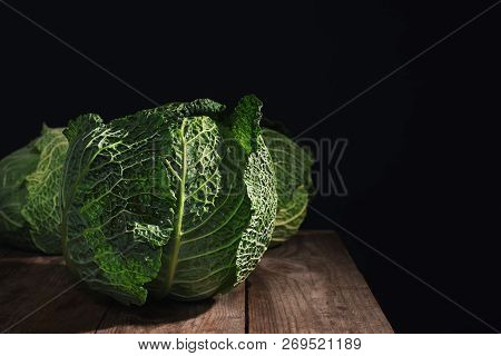Savoy Cabbage On Wooden Table Against Black Background. Space For Text