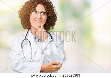 Middle ager senior doctor woman over isolated background looking confident at the camera with smile with crossed arms and hand raised on chin. Thinking positive.