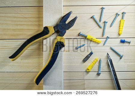 Screws, Dowels, Screwdriver And Pliers Lie On The Boards. Locksmith Work With Wood.