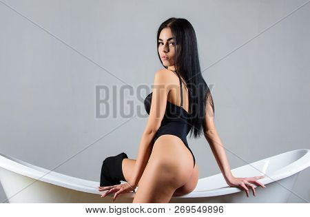 Erotic And Desire. Fashion Sexy Model Seductive Posing On Bathtub. Woman Sexy Buttocks Wear Bodysuit
