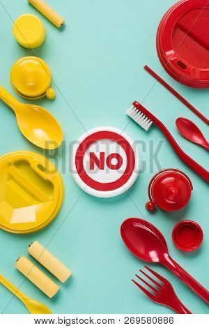 Top View Of No Sign And Disposable Red And Yellow Plactic Garbage On Blue Background