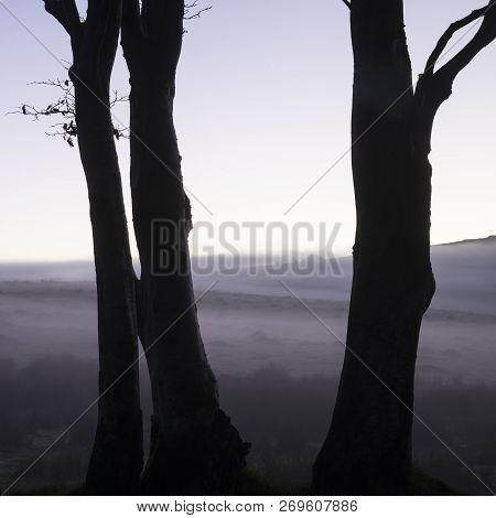 Stunning Foggy Sunrise Landscape Over The Tors In Dartmoor Revealing Peaks Through The Mist