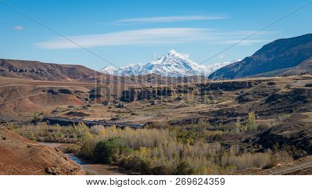 Erzincan, Turkey - August 2018: View Of A Valley With A Train And Railway With Snow Capped Mountains