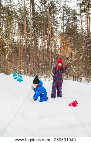 Happy Children In A Winter Snow-covered Forest With Gift Boxes.