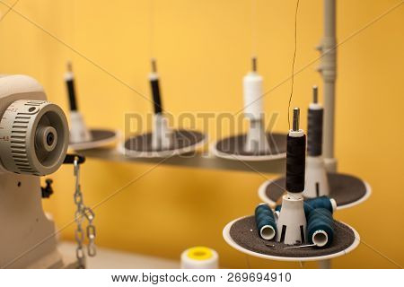 String Of Black And White Threads On White Sewing Machine On Yellow Wall