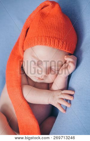 A Naked Newborn Baby Sleeps In A Christmas Hat.