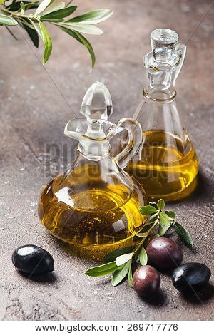 Olive Oil In A Glass Bottle And Olive Branch On Brown Stone Table