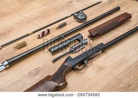 Disassembled Shotgun Parts And Cleaning Kit On The Wooden Background