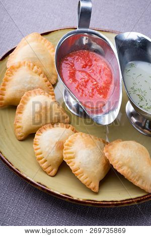 Small Pirogi Stuffed With Meat Served On A Plate With Sauces