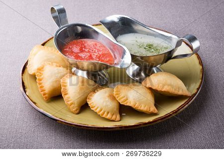 Small Pirogi Stuffed With Meat Served On A Plate With Sauces