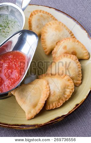 Small Pirogi Stuffed With Meat Served On A Plate With Sauces