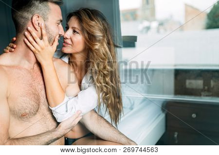 Back View Of Woman In Black Panties Holding Her Bra While Man Is Lying On Bed