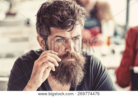 Man With Beard And Mustache Sits Outdoor At Cafe Terrace. Bearded Man On Calm Face Looks Sad And Tro