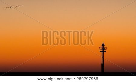 Abstract Photo Of A Light Signal Or Light Buoy Against A Brightly Colored Sky With Beautiful Intense