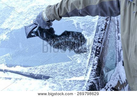 A Man Is Scraping The Windshield Of A Car