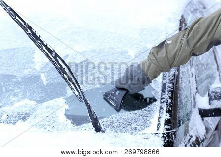 A Man Is Scraping The Windshield In Winter