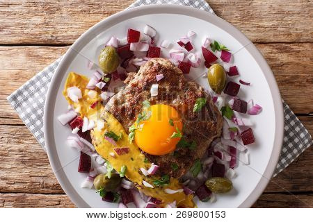Fried Beef Tartare Or Parisian Steak - Pariserbof With Egg,  Vegetables And Mustard Close-up On A Pl