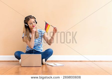 Young Woman With Germany Flag Using A Laptop Computer Against A Big Interior Wall