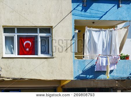 Turkish Flag In The Window - Near The Balcony Dries Linen. Typical House In A Poor Quarter Of Istanb