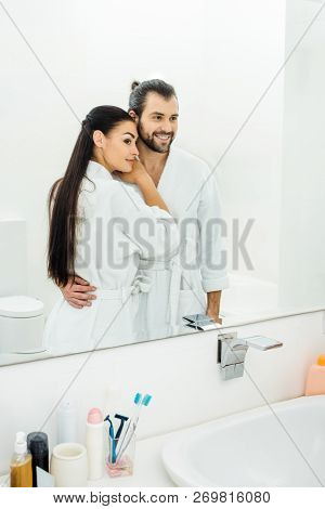 Tender Couple  In White Bathrobes Hugging In Bathroom At Morning