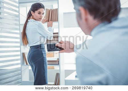 Serious Woman Staying Near Shelves With Documents
