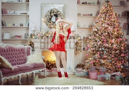 Sexy Woman In Red Dress Next To The Christmas Tree In The Room.