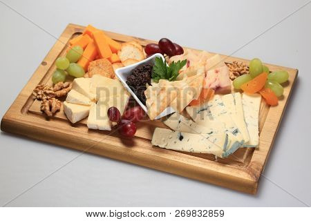 Mix Cheese On A Oard With Some Fruits On The Side