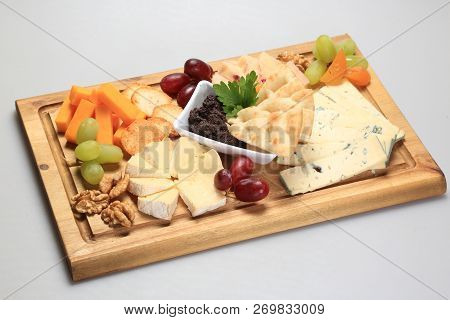 Mix Cheese On A Oard With Some Fruits On The Side