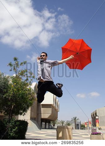 Beer Sheva,  Israel - June 11, 2011:  Young Man Jumping With A Red Umbrella In University Campus In 