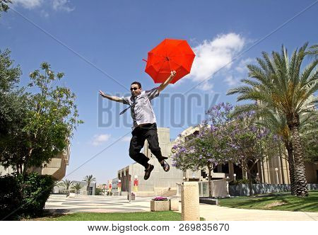 Beer Sheva,  Israel - June 11, 2011: Young Man Jumping With A Red Umbrella In University Campus In B