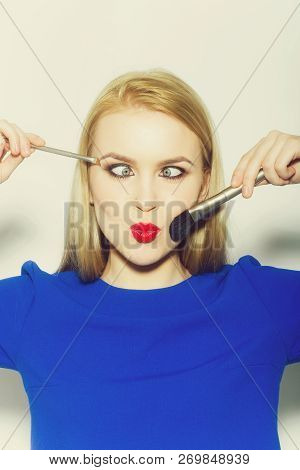 Woman Squinting Eyes On Duck Face With Red Lips. Funny Girl With Makeup Brushes And Long Blond Hair 