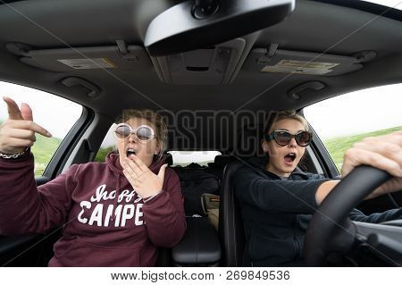 Two Woman Inside Of A Car Looked Shocked, Scared And Astounished As They Are Driving