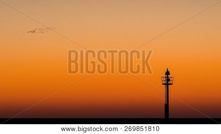 Abstract Photo Of A Light Signal Or Light Buoy Against A Brightly Colored Sky With Beautiful Intense