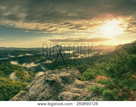 Tripod Without Camera On Peak Ready For Photography. Sharp Autumn Rocky Peaks Increased From Green V