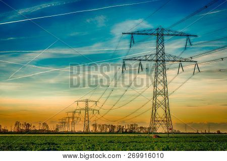 Overview Of Power Pylons And High Voltage Lines In A Long Row In A Rural Landscape. The Photo Was Ta