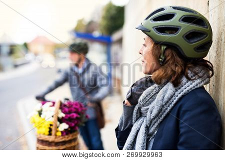 Active Senior Couple With Electrobikes Standing Outdoors On A Road In Town.