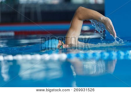 Photo of young athlete in blue cap swimming in pool