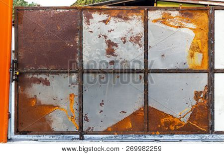 Gate Is Made Of นld Rusted Galvanized Metal Sheet With Old Locked Padlock. Rusty Surface Caused By O