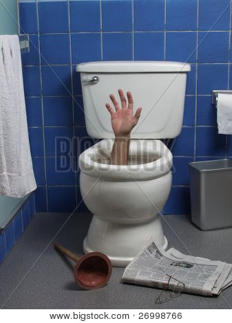  Hand reaches up through the seat from out of a toilet in a domestic bathroom.