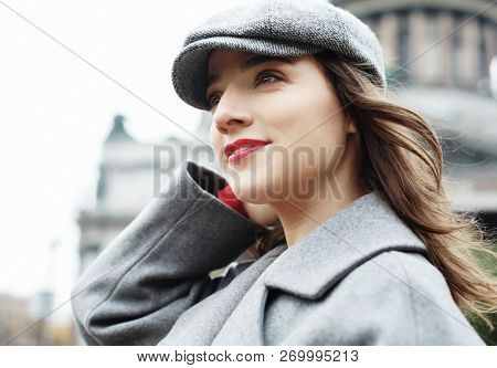 Lifestyle  and people concept: Close-up portrait of young woman in elegant gray coat standing on the street in autumn day. Outdoor photo of fashionable female  walking around city in autumn vacation