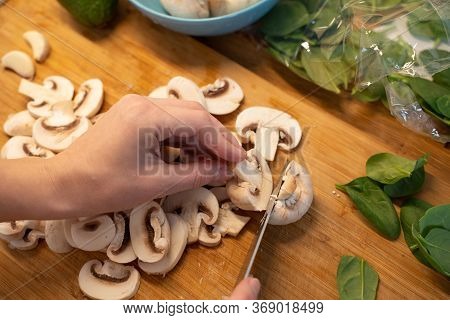 Woman Cutting Mushroom On Table, Close-up. Hands Cutting Mushrooms On A Cutting Board. Young Woman C