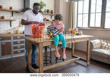Dark-skinned Tall Father And His Cute Daughter Speding Time At Home Daling With Housework