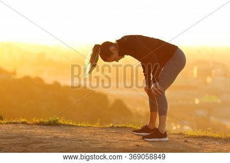Side View Portrait Of A Tired Runner Resting After Exercise In City Outskirts At Sunset