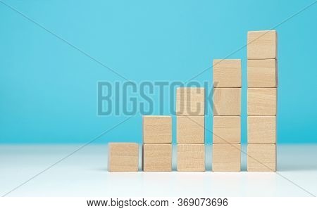 Wooden Blocks As A Pyramid Staircase On Blue Background. Success, Growth, Win, Victory, Development 