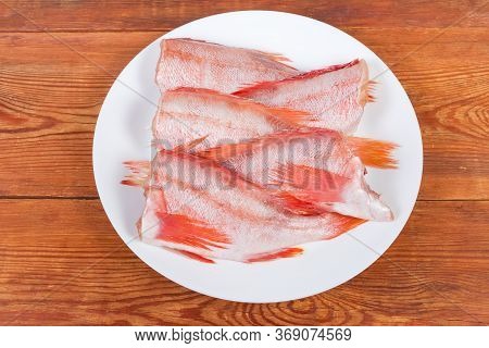 Raw Headless Gutted Carcasses Of Redfish Also Known As Ocean Perch On The Dish On The Rustic Table, 