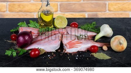 Raw Headless Gutted Carcasses Of Redfish Also Known As Ocean Perch Among The Spices, Fresh Vegetable