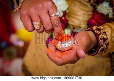 The Groom's Hand Holding Sindur Or Vermilion Before Applying On The Bride`s Hair-parting.