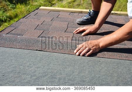 A Building Contractor Is Installing  Dimensional Asphalt Roof Shingles On The Underlayment Of The Ho