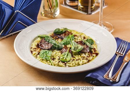 Risotto With Spinach And Chicken Liver Garnished With Spinach Leaves And Parmesan Cheese. Restaurant